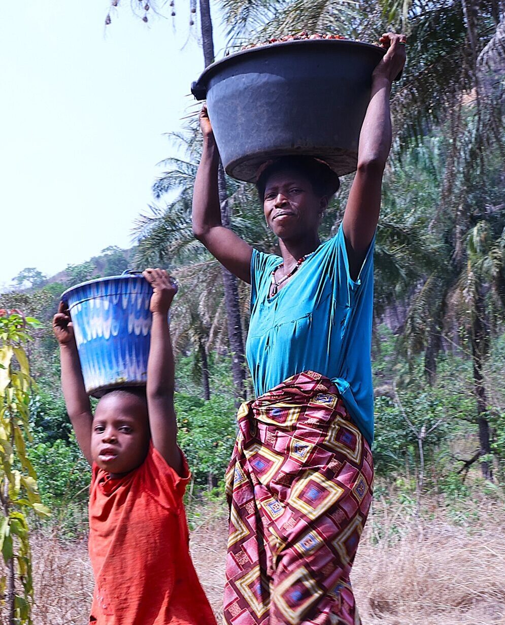 Madre e hijo de Guinea Conakry, transportando comida en sus cabezas, escena cotidiana de Guinea Conakry.