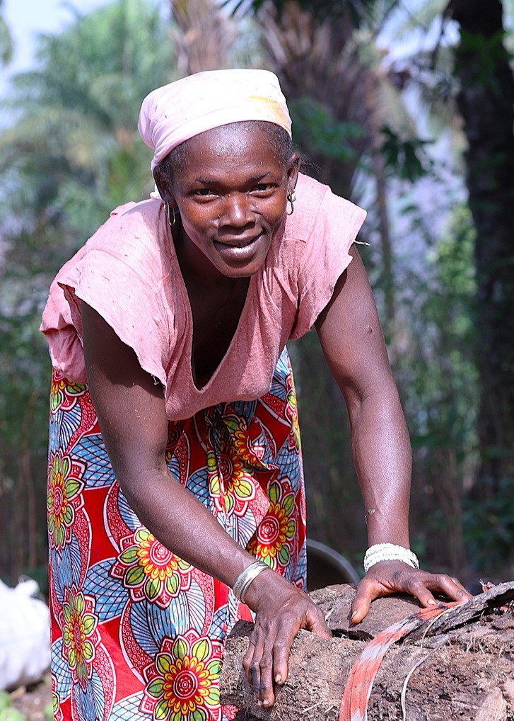 Mujer guineana trabajando en un entorno rural rodeado de vegetación.